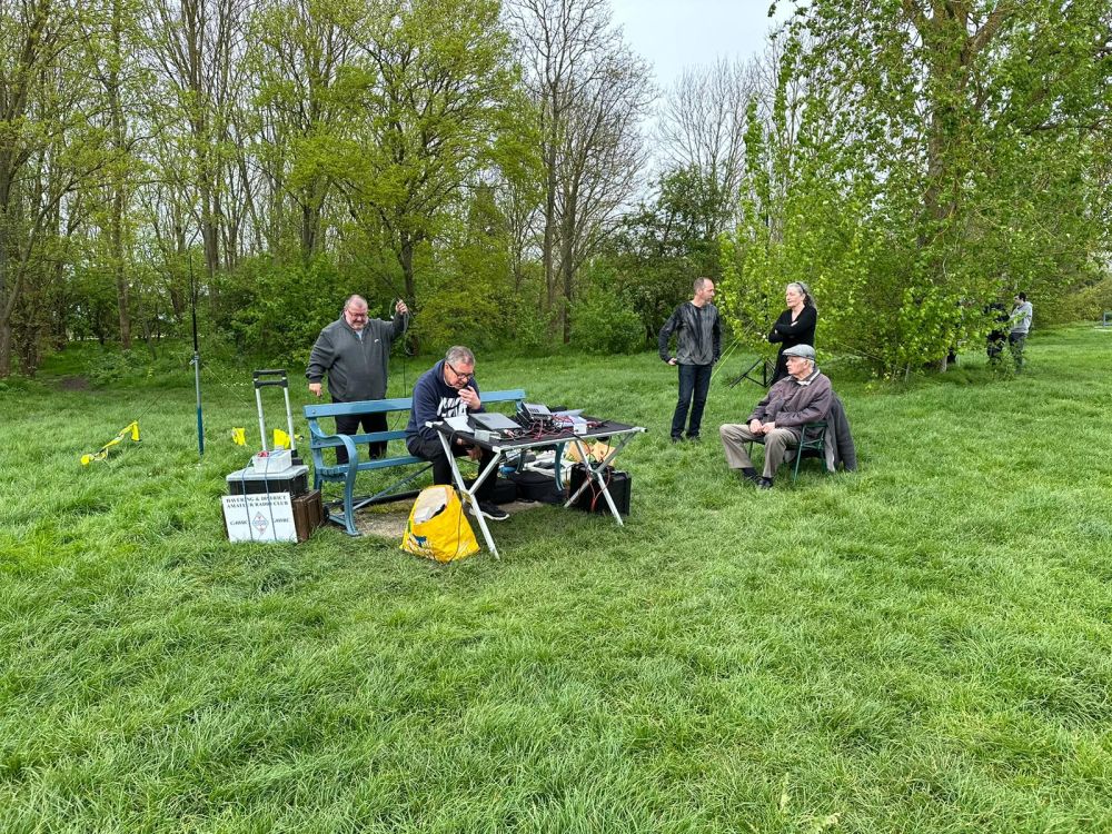 Neil G50YY Kevin 2E0WKV operating the radio Kevin M7MJW talking to visitor and Terry M6AMI sitting down
